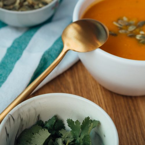 soup in white ceramic bowl beside stainless steel spoon